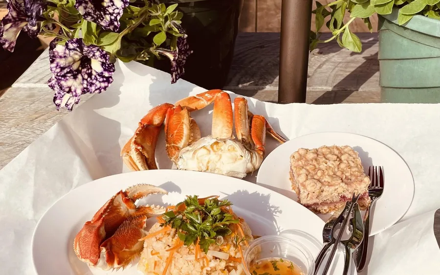 Plates of Alaskan crab legs and sides on a table by the water